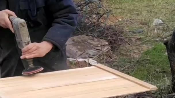 Mestre trabalha com um moedor em madeira ao ar livre, vídeo em câmera lenta, com o efeito de vídeo antigo — Vídeo de Stock