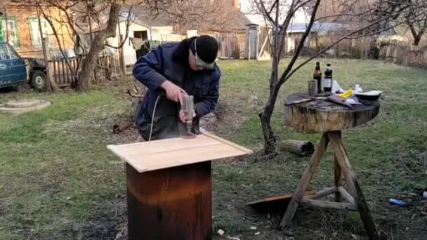 Mestre trabalha com um moedor na madeira ao ar livre, vídeo — Vídeo de Stock