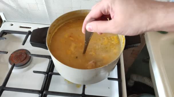 Cocine revolviendo la sopa de guisantes hirviendo con una cuchara en la estufa — Vídeo de stock