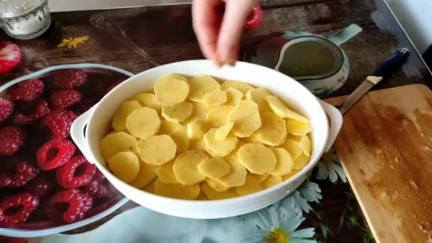 Mujer de la sal en rodajas de patatas en un plato para hornear, 4K video — Vídeo de stock