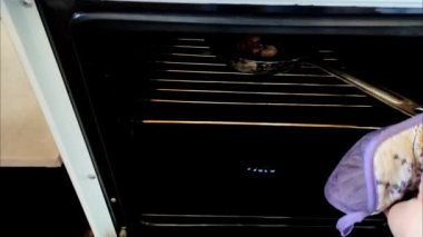 Aşçı fırından fırında pişmiş tavuk budu çıkarır.