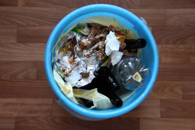 Yemek artıkları ve tavuk kemikleri olan çöp tenekesi.