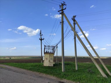 Kırsalda eski trafo kutusu ve elektrik hatları var.