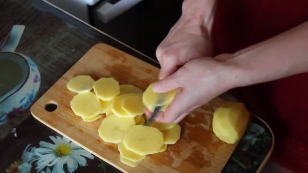 Mujer corta patatas sobre la tabla de cortar en la mesa,, primer plano, 4K video — Vídeo de stock