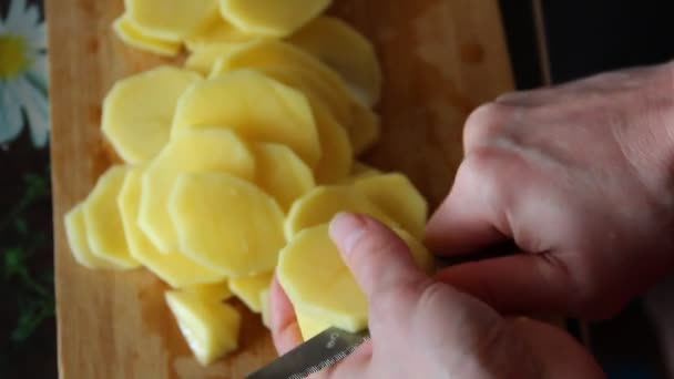 Mujer corta patatas sobre la tabla de cortar en la mesa,, primer plano, 4K video — Vídeo de stock