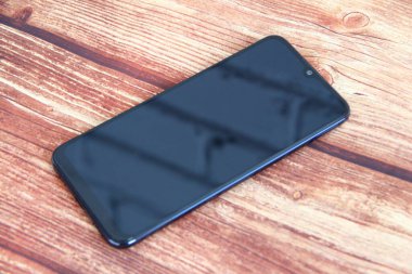 Ahşap arka planda siyah ekranlı akıllı telefon