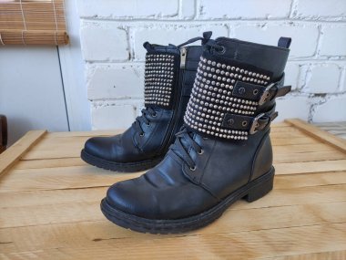 Ahşap bir arka planda yapay elmaslarla siyah kadın botları.