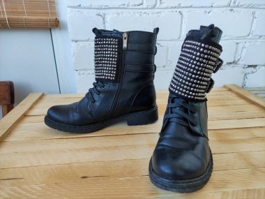 Ahşap bir arka planda yapay elmaslarla siyah kadın botları.