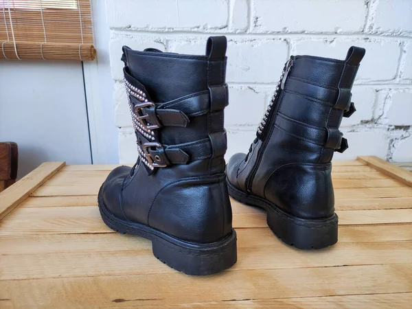 Black women\'s boots with a rhinestones on a wooden background