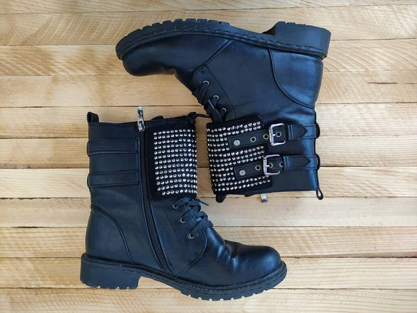 Black women\'s boots with a rhinestones on a wooden background