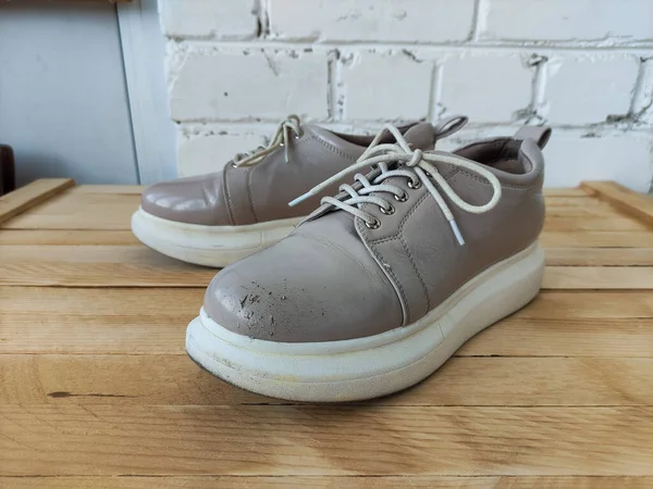 Beige female patent leather platform sneakers on the wooden background