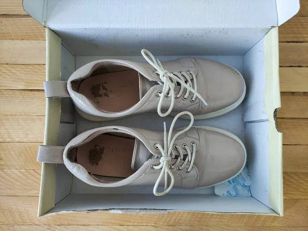 Beige female patent leather platform sneakers in a box