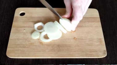 Aşçı mutfaktaki kesme tahtasındaki soğanı keser.