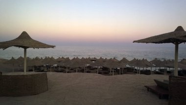 Mısır 'da günbatımının arka planında şemsiyeli plaj