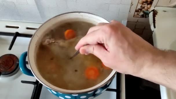 Cocinar revolviendo sopa de pollo con verduras en la cocina — Vídeo de stock