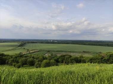 Manzara - vadi, tarlalar, orman ve gökyüzü bulutlarda