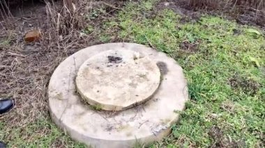 Adam bahçede bir foseptik tankı kapağı açıyor, kışın ya da sonbaharda, 4K video.