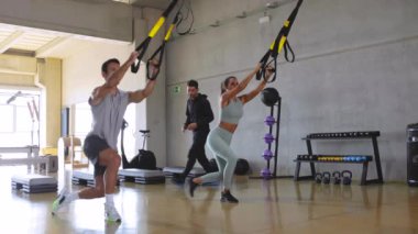 TRX sırasında bir erkek ve kadına antrenörlük yapan kişisel antrenör.. 