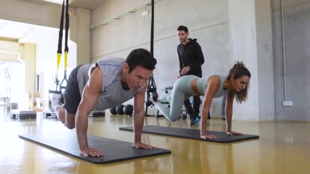 Sportowy mężczyzna i kobieta trening nóg i brzucha z trx paski fitness w siłowni. — Wideo stockowe