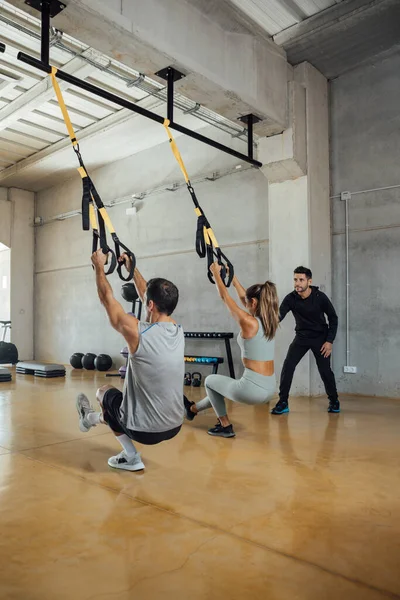 Fitte Männer und Frauen trainieren mit einem Personal Trainer im Fitnessstudio. — Stockfoto