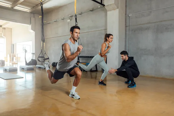 Fitness trainer entrena a hombres y mujeres para hacer ejercicio de embestida en un gimnasio. — Foto de Stock