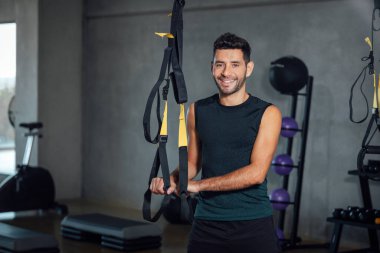 Büyük endüstriyel bir spor salonunda kameraya bakan kendine güvenen bir sporcu..