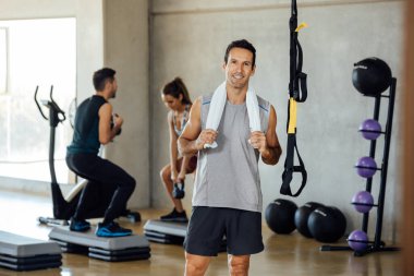 Spor giyim bölümündeki yakışıklı genç adam spor salonunda gülümseyen kameraya bakıyor..