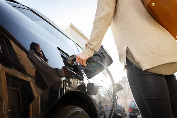 Gewassen weergave van de vrouw houdt conector pluggen in handen om elektrische auto op te laden. — Stockfoto