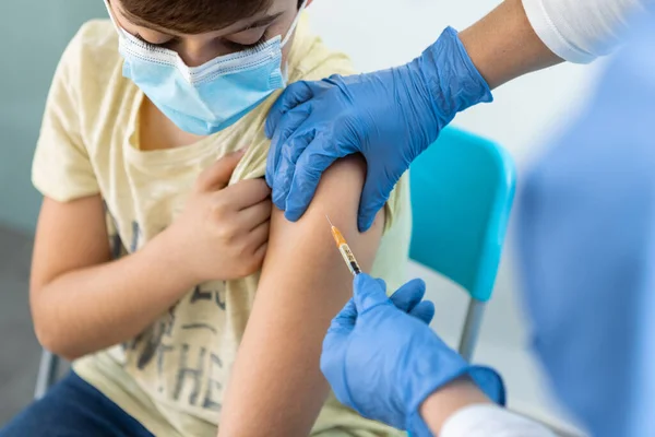 Enfermera que inyecta la vacuna Covid-19 en el brazo del muchacho para la protección del virus en la clínica. —  Fotos de Stock