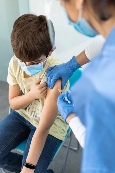 Sjuksköterska som injicerar Covid-19 vaccin vid Boy In Arm för virusskydd på kliniken. — Stockfoto