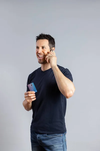 Hombre sonriente habla por teléfono y tiene tarjeta de crédito. —  Fotos de Stock