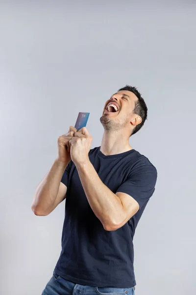 Hombre afortunado sosteniendo tarjeta de crédito con ambas manos —  Fotos de Stock