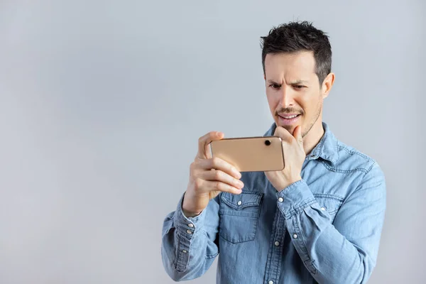 Hombre curioso viendo un video o foto en un teléfono inteligente. —  Fotos de Stock