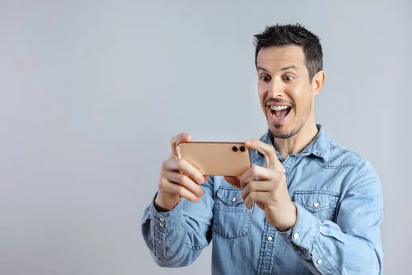 Hombre sorprendido ve un video o foto en un teléfono inteligente. —  Fotos de Stock