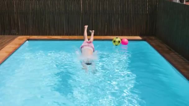 男の子のダイビングブルーウォータープールに飛び込み 透明な水を振りかける 晴れた日に水中で泳ぐ子供 夏休みにリラックスした少年 スローモーション — ストック動画