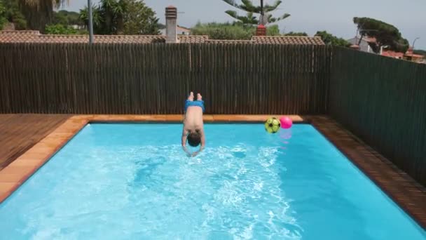 男の子のダイビングブルーウォータープールに飛び込み 透明な水を振りかける 7歳の子供は晴れた日に水中で泳いでいます 夏休みにリラックスした少年 スローモーション 4Kビデオ — ストック動画