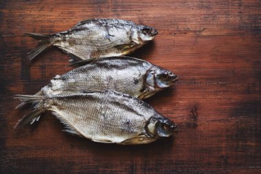 Kurutulmuş tuzlu balık. Eski ahşap bir masa yüzeyinde mavi çipura. Üst manzara, kopyalama alanı..