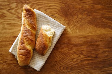 Fransız usulü çıtır baget keten bir peçetenin üzerinde dokulu bir meşe sehpası üzerinde duruyor. Üst manzara, fotokopi alanı. Fırın ürünleri