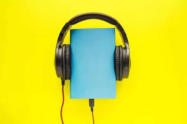 Buch Blauem Umschlag Und Schwarzen Kopfhörern Auf Leuchtend Gelbem Hintergrund — Stockfoto