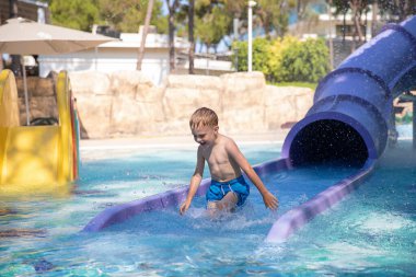 Gülümseyen sevimli bir çocuk Aquapark 'taki havuzda eğleniyor. Havuzda hareketlilik var. Yaz tatili kavramı, dinlenme, eğlence.