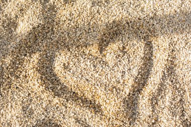 Açık renkli küçük taşlara boyanmış bir kalp. Arkaplan, taştan yapılmış doku.