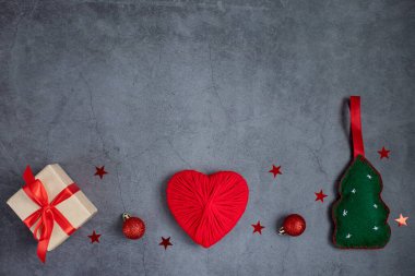 Noel aksesuarları, bir hediye kutusu, yeni yıl ağacı, toplar, koyu gri arka planda bir kalp. Yeni Yıl, Noel kavramı.