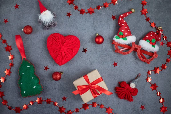 Noel aksesuarları, bir hediye kutusu, yeni yıl ağacı, toplar, kalp, koyu gri arka planda gözlük. Yeni Yıl, Noel kavramı.