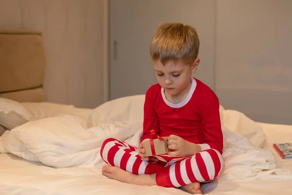 Niño Pequeño Pijama Rojo Navidad Desempaca Regalo Sentado Cama Concepto — Foto de Stock