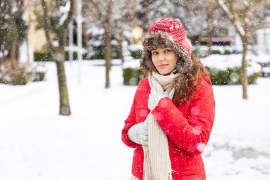 Genç gülümseyen kadın şehirde kışın karlı gününün tadını çıkarıyor.