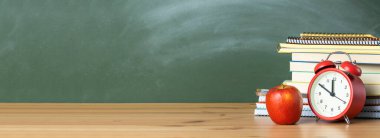 Okul masasında çalar saat ve ders kitapları var. Okula geri dön.