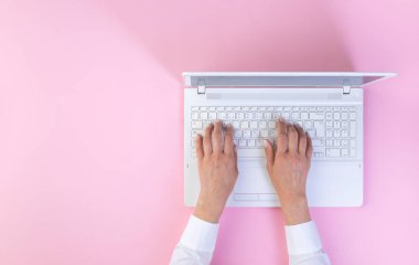 Üst düzey bir iş kadını, ofiste dizüstü bilgisayarı olan pembe bir masaya el koydu..