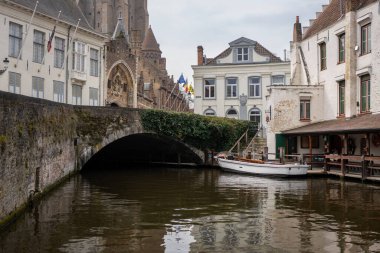Moored tour boat next to a vine covered bridge in the heart of Brugge Belgium