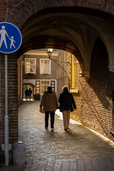 People passing through a back alley at sunset in Delft Netherlands