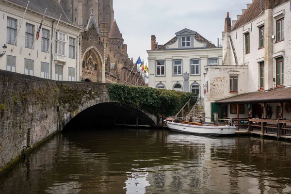 Moored tour boat next to a vine covered bridge in the heart of Brugge Belgium